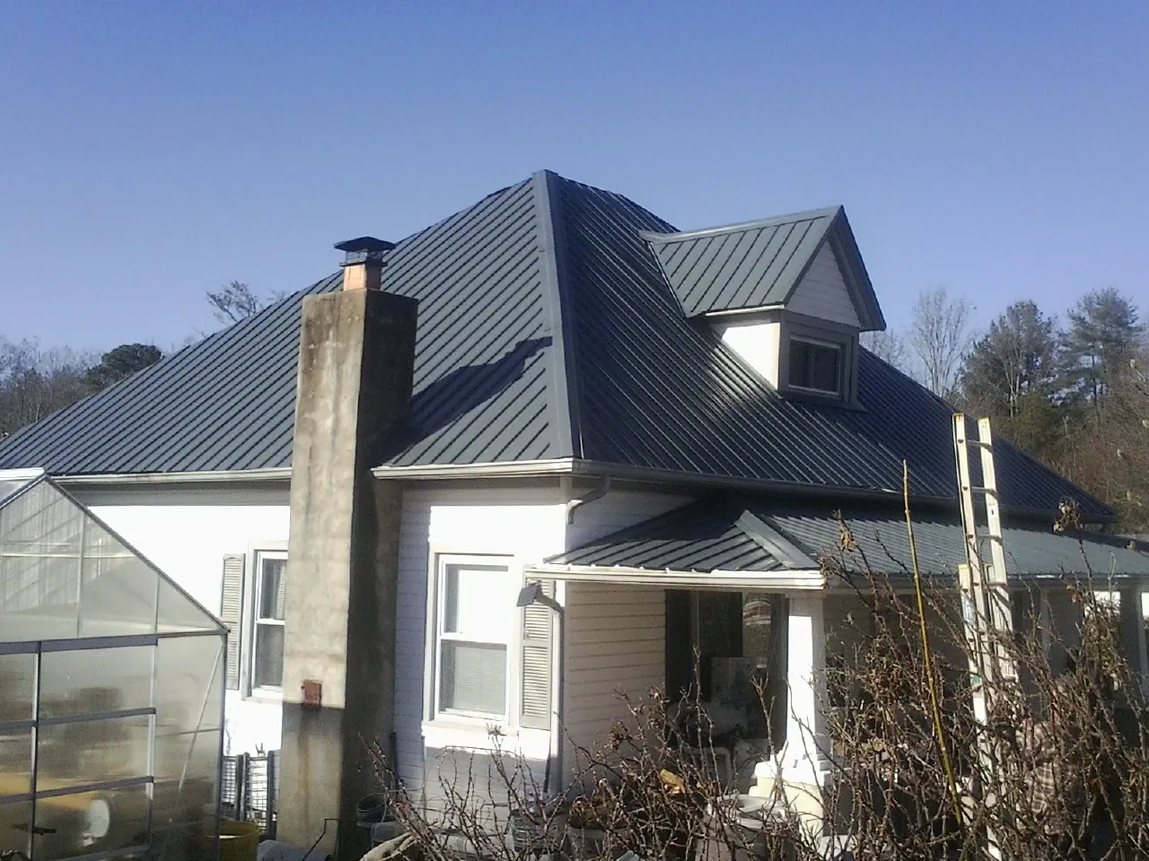 Dark blue standing seam metal roof on a white farmhouse with dormer — Slate & Tile Roof Repair by Roofing Brothers in West Cornwall