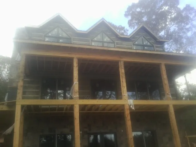 Dormers and porch framing on a large log home under construction — Roof Coating work by our crew in West Cornwall
