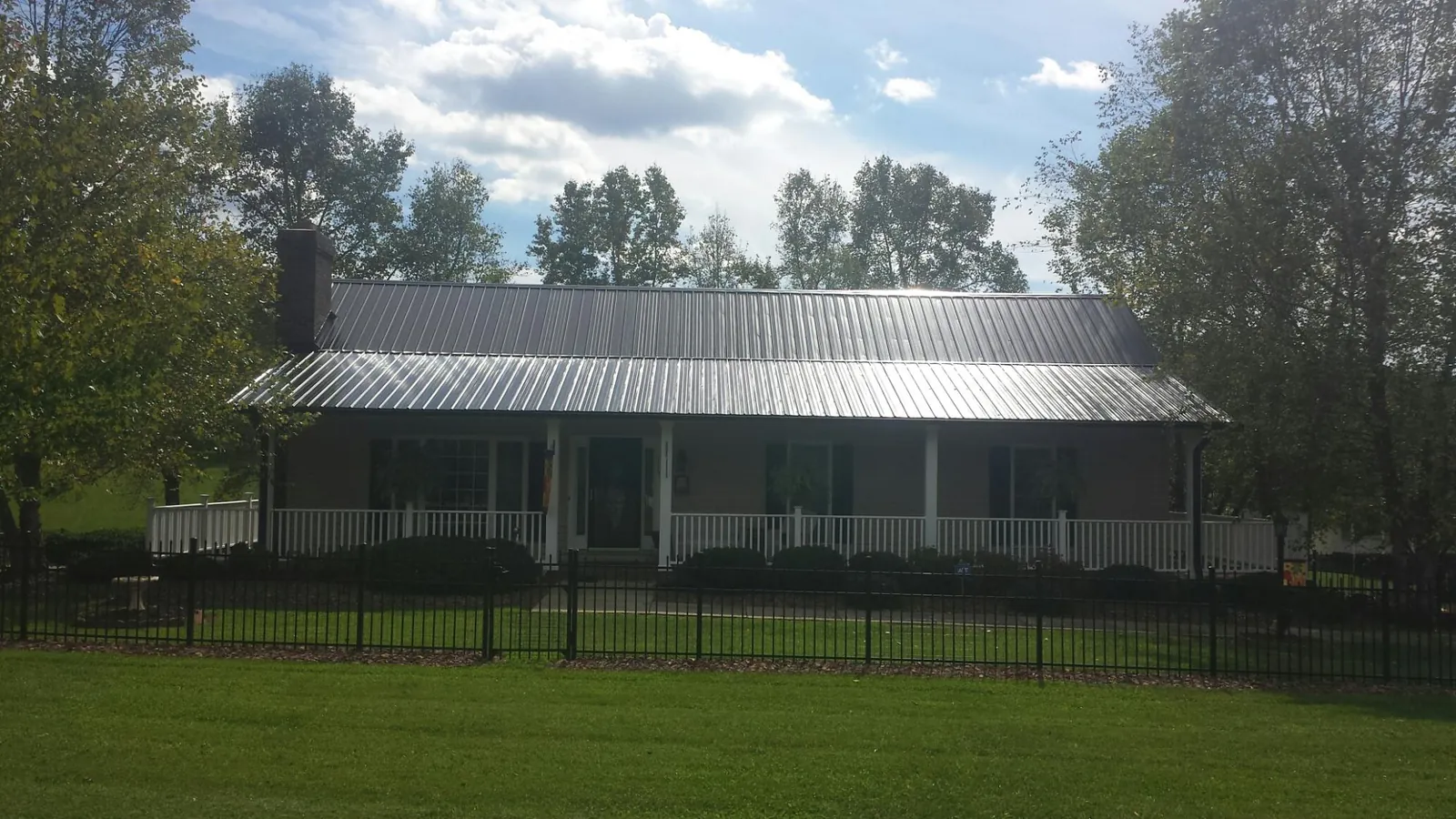 Gray metal roof on a brick ranch with a full width front porch — Gutter Guard Installation work by our crew in West Cornwall