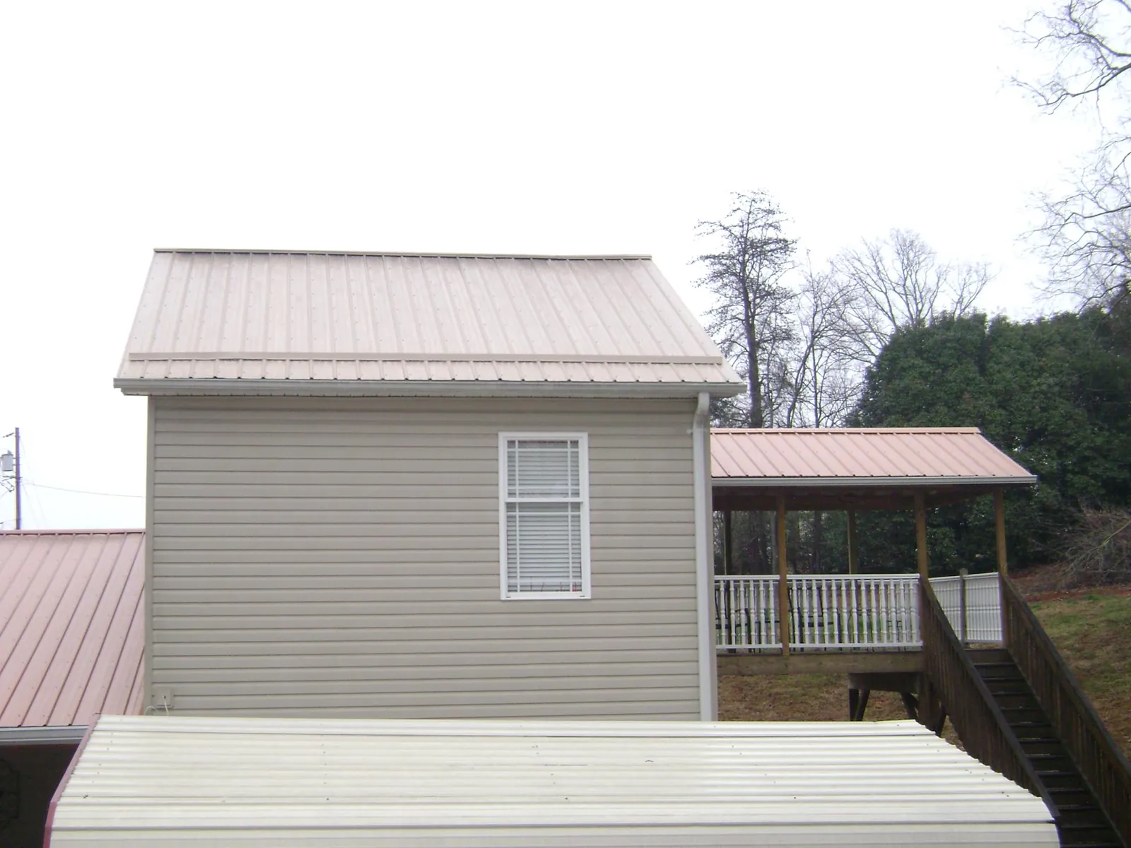 Tan metal roofs on a two story addition and attached porch, from a Roof Replacement job in West Cornwall
