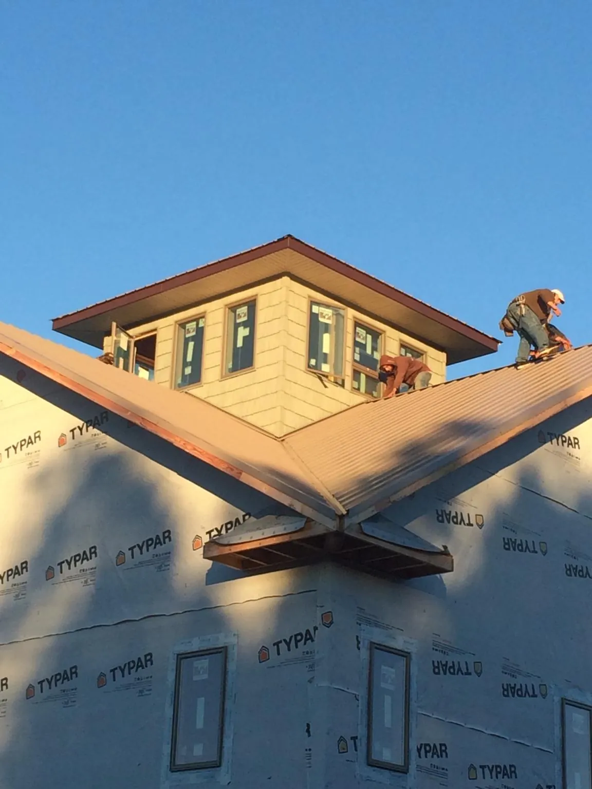 Roofers working around a rooftop cupola on a new metal roof at sunset — Roof Waterproofing in West Cornwall by Roofing Brothers